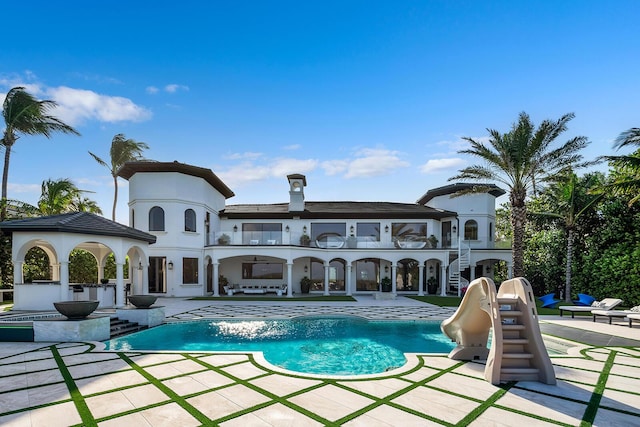 back of property featuring a balcony, exterior kitchen, and a patio area