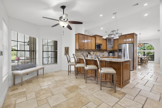 kitchen featuring ceiling fan, light stone counters, high vaulted ceiling, decorative backsplash, and appliances with stainless steel finishes