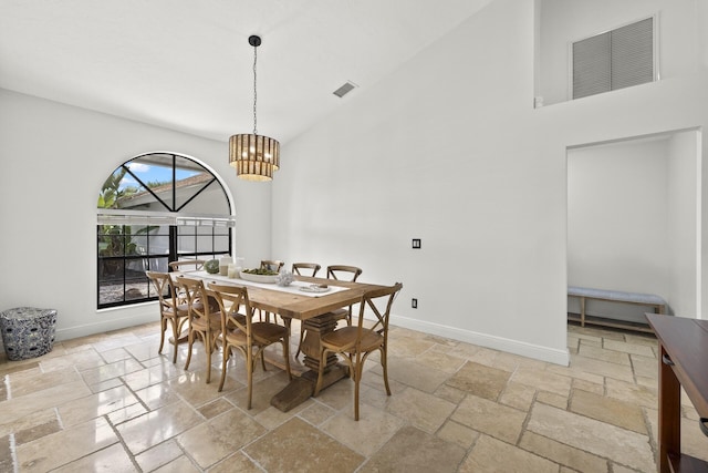 dining area with a towering ceiling and a notable chandelier