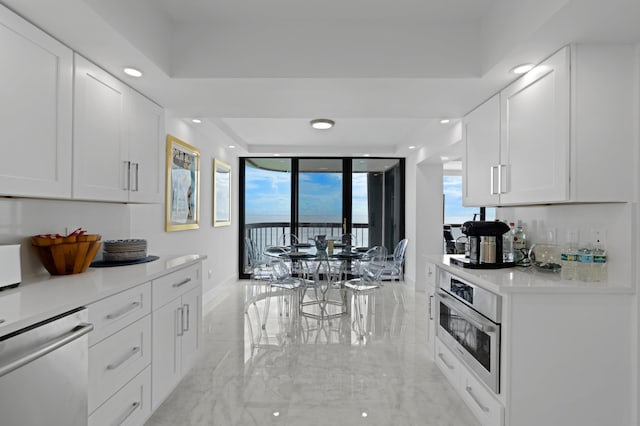 kitchen featuring appliances with stainless steel finishes, light tile patterned floors, white cabinets, and a tray ceiling