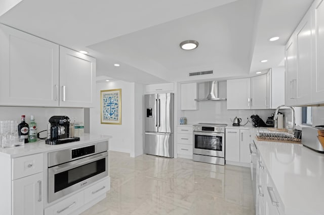 kitchen featuring white cabinetry, light tile patterned flooring, wall chimney exhaust hood, sink, and appliances with stainless steel finishes