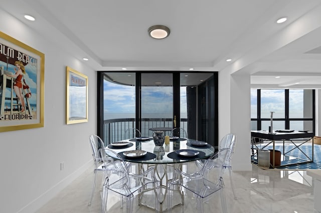 dining area featuring light tile patterned floors and a tray ceiling