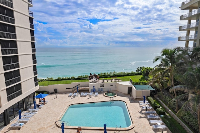 view of pool with a water view and a patio