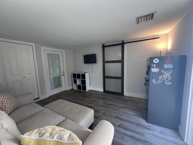 living room featuring a textured ceiling, dark hardwood / wood-style floors, and a barn door