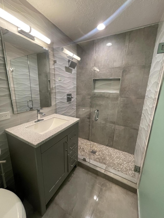 bathroom with vanity, a textured ceiling, and a shower with door