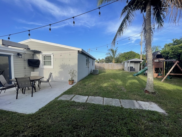 view of yard with a playground, a patio area, a storage shed, and central AC unit