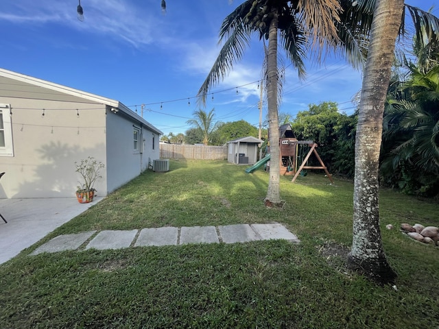 view of yard with a playground, central AC, and a storage shed