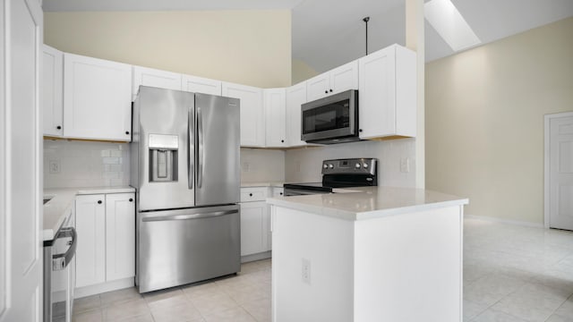 kitchen featuring light tile patterned floors, kitchen peninsula, stainless steel appliances, lofted ceiling, and white cabinets