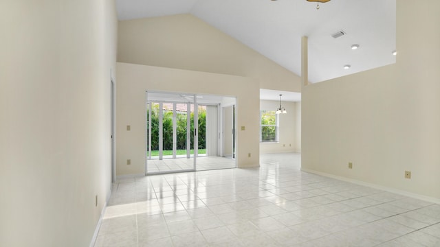 spare room featuring light tile patterned floors, ceiling fan with notable chandelier, and high vaulted ceiling