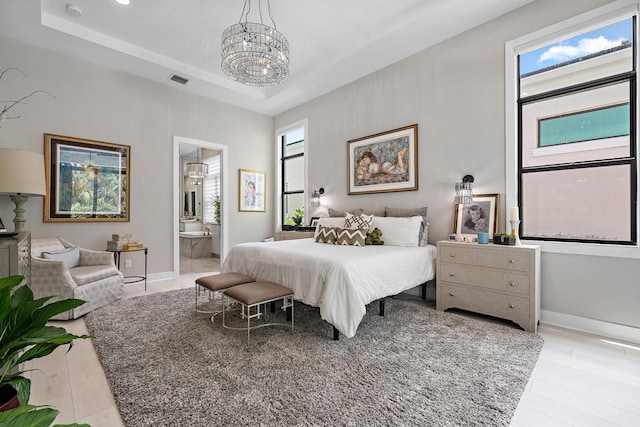 bedroom with a tray ceiling, baseboards, a chandelier, and light wood-style flooring