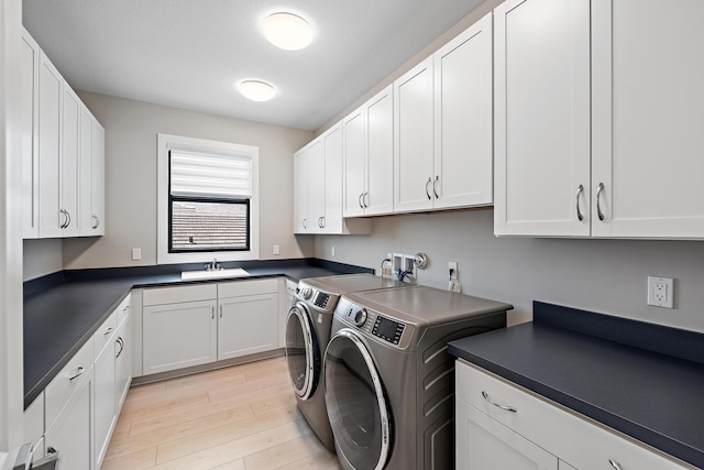 laundry area featuring light hardwood / wood-style floors, sink, cabinets, and washing machine and clothes dryer