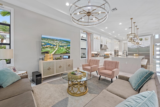 living room featuring sink, a chandelier, and a tray ceiling