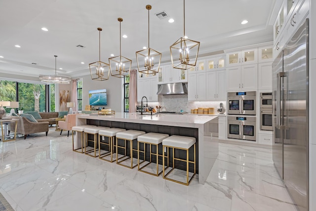 kitchen with appliances with stainless steel finishes, tasteful backsplash, pendant lighting, white cabinetry, and a spacious island