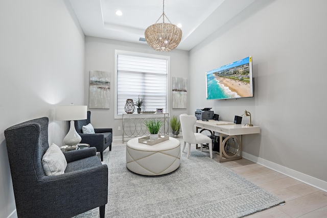 living area with light hardwood / wood-style floors, a raised ceiling, and a notable chandelier