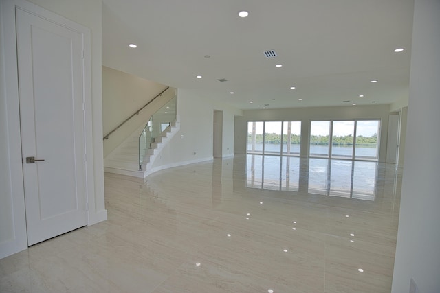 unfurnished living room with light tile patterned flooring and a water view