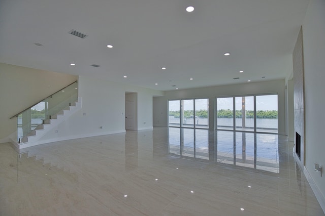 unfurnished living room with a water view and light tile patterned floors