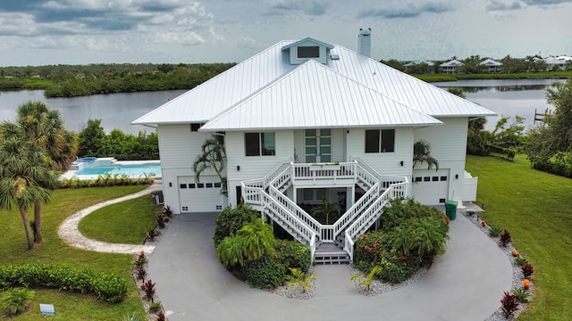 raised beach house with a porch, a garage, and a water view