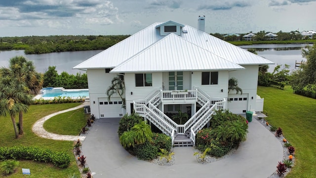 13064 Via Flavia, Placida, FL 33946 - view of front of house with an attached garage, covered porch, a water view, a front lawn, and concrete driveway