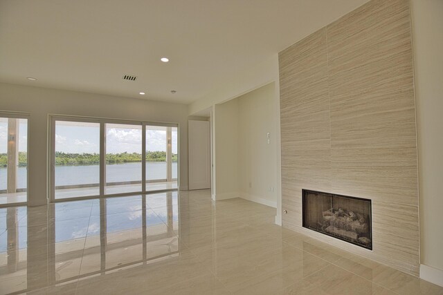 13064 Via Flavia, Placida, FL 33946 - unfurnished living room with a fireplace, a water view, light tile patterned floors, baseboards, and recessed lighting