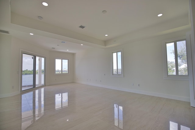 tiled spare room featuring a wealth of natural light and a raised ceiling