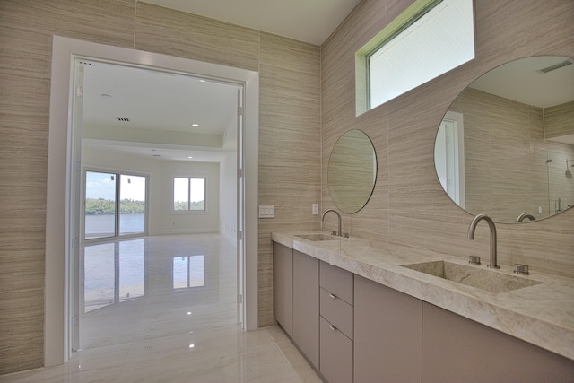 bathroom featuring tile patterned flooring, tile walls, and dual bowl vanity