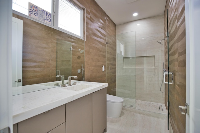 bathroom featuring vanity, tile walls, a shower with shower door, toilet, and tile patterned flooring