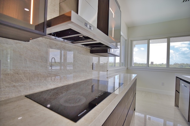 kitchen featuring stainless steel dishwasher, backsplash, a healthy amount of sunlight, and wall chimney range hood