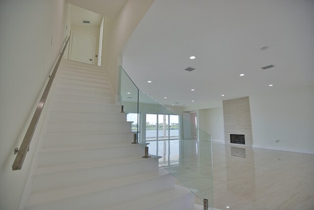 stairs with a fireplace and light tile patterned floors