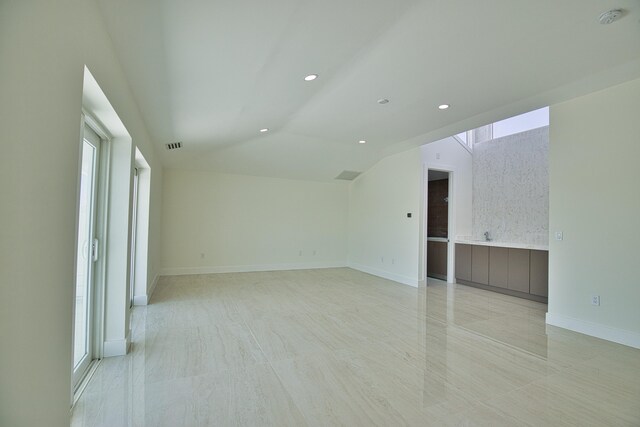 unfurnished room with light tile patterned flooring and vaulted ceiling