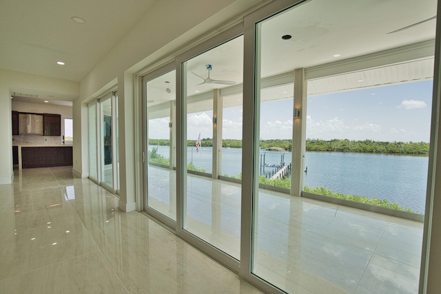 entryway featuring tile patterned floors, a water view, a wealth of natural light, and ceiling fan