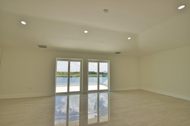 tiled spare room featuring a water view