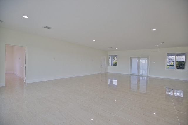 empty room with french doors, a wealth of natural light, and light tile patterned floors