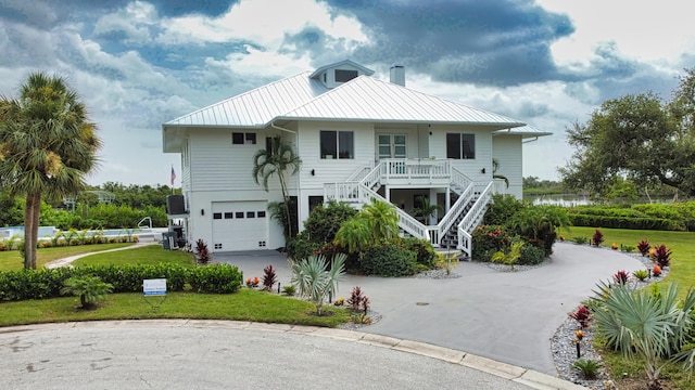 coastal home with a porch, a garage, and a front yard