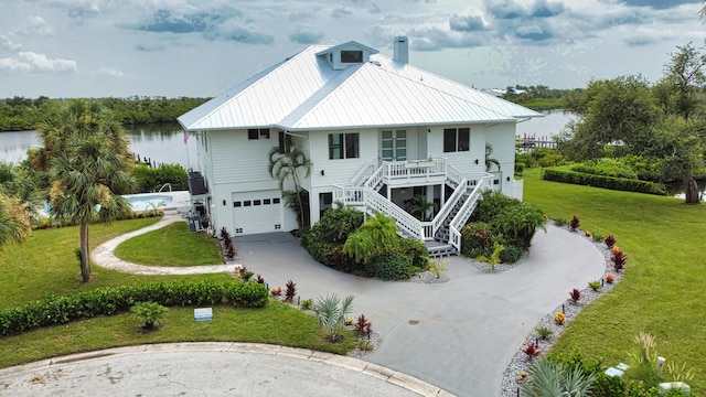 view of front facade featuring a garage, a porch, a water view, and a front yard