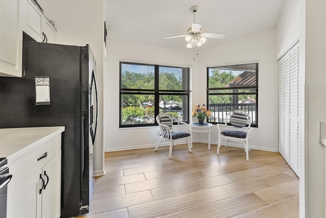 kitchen featuring white cabinetry, black fridge, ceiling fan, and light wood-type flooring