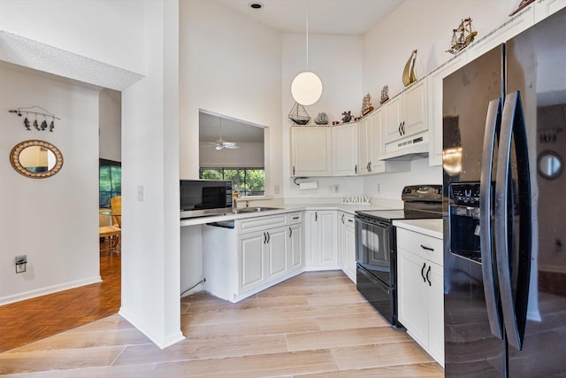 kitchen with black appliances, hanging light fixtures, ceiling fan, a high ceiling, and white cabinets