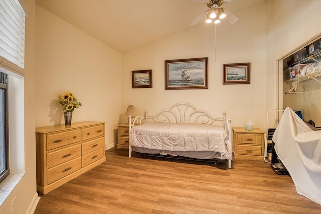 bedroom featuring multiple windows, a closet, lofted ceiling, ceiling fan, and light hardwood / wood-style flooring