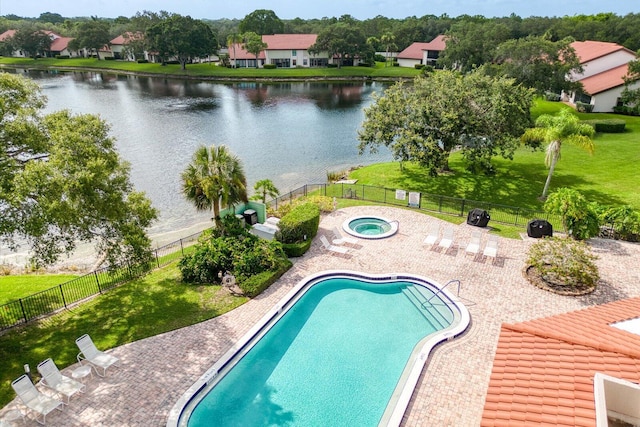 view of swimming pool featuring a hot tub, a water view, a yard, and a patio area