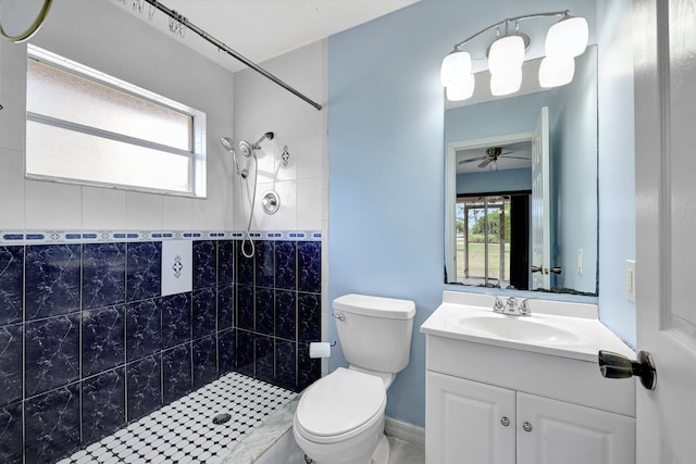 bathroom with ceiling fan, vanity, toilet, and a tile shower