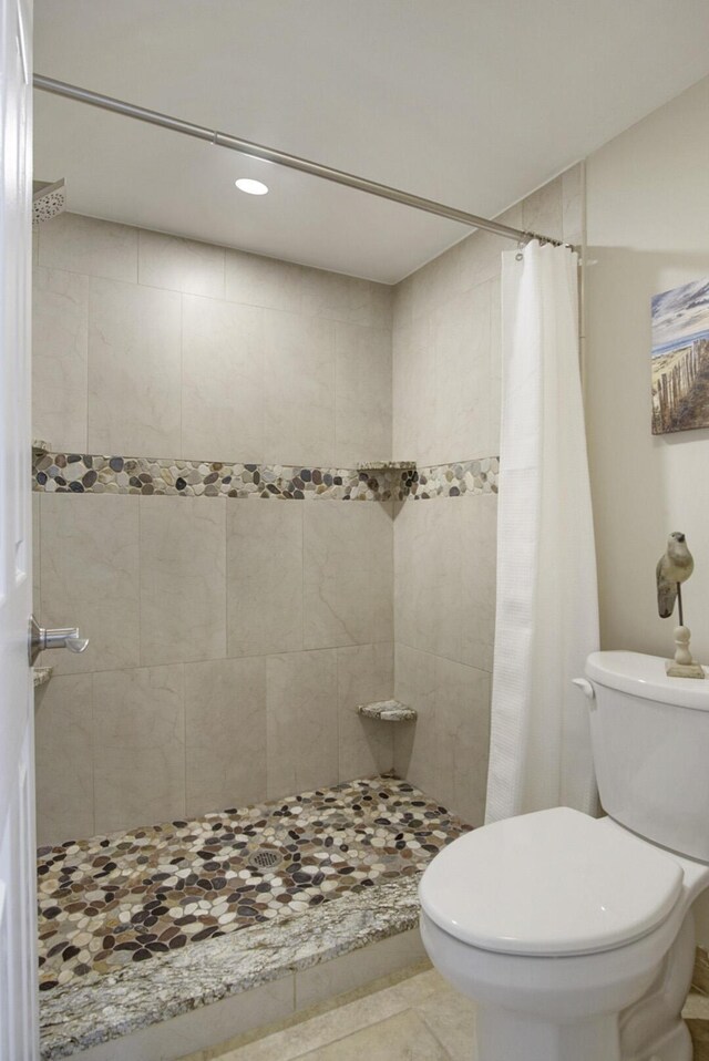 bathroom with a shower with shower curtain, toilet, and tile patterned floors