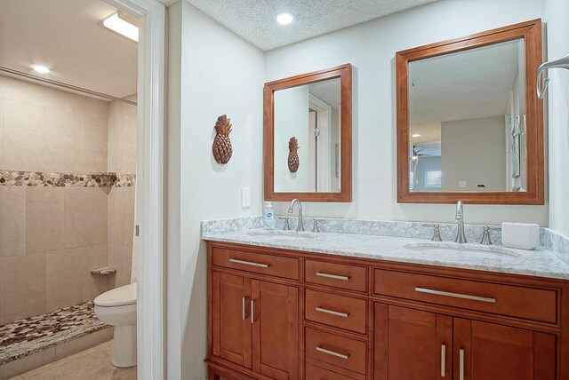 bathroom featuring tiled shower, vanity, a textured ceiling, and toilet