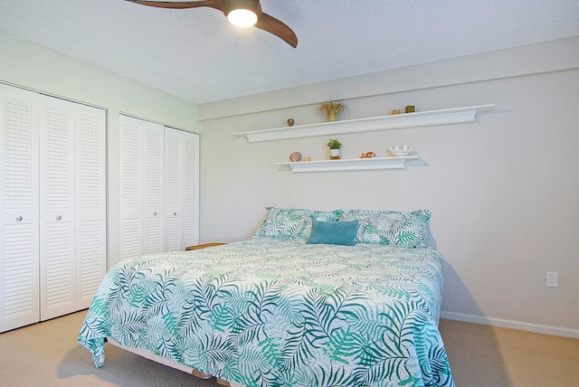 bedroom with multiple closets, ceiling fan, and light carpet