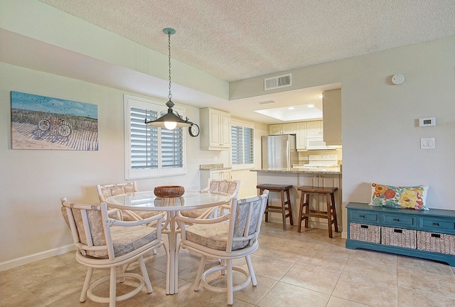 dining room with light tile patterned floors, a textured ceiling, and a tray ceiling