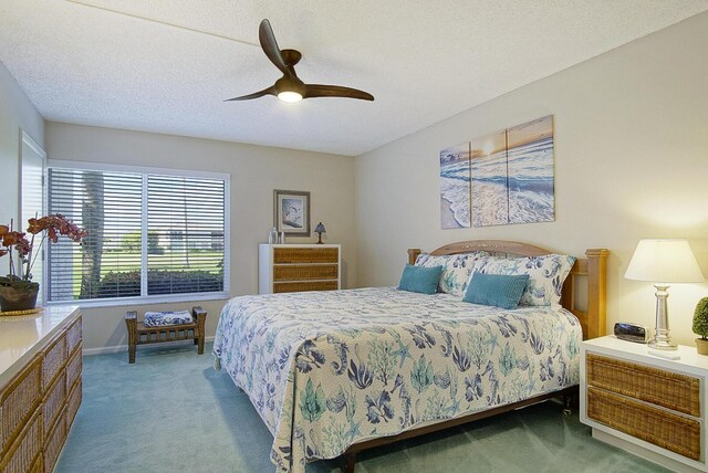 carpeted bedroom with ceiling fan and a textured ceiling