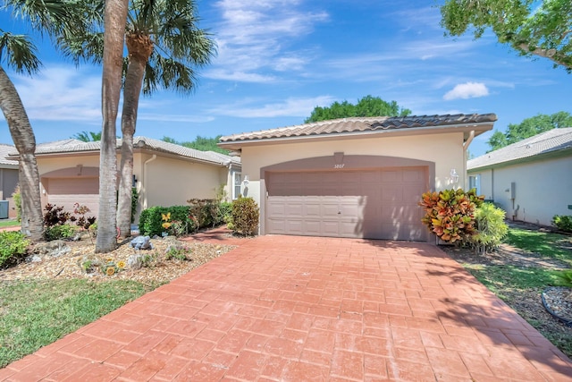 mediterranean / spanish-style house featuring a tiled roof, decorative driveway, an attached garage, and stucco siding