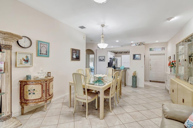 dining space featuring light tile patterned floors, visible vents, arched walkways, and baseboards