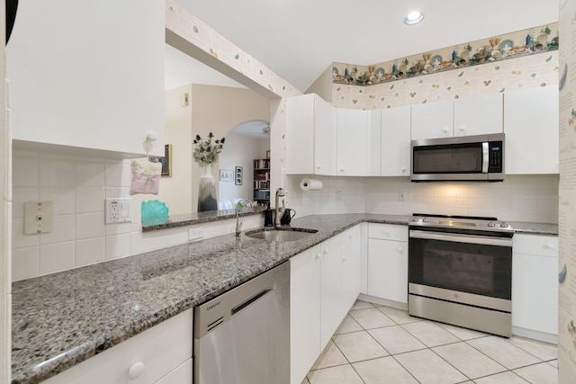 kitchen featuring a sink, white cabinetry, appliances with stainless steel finishes, light tile patterned floors, and light stone countertops
