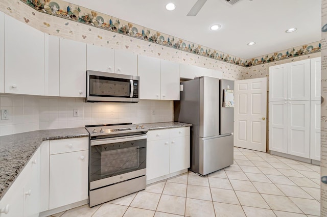 kitchen featuring light stone counters, tasteful backsplash, appliances with stainless steel finishes, white cabinets, and light tile patterned floors