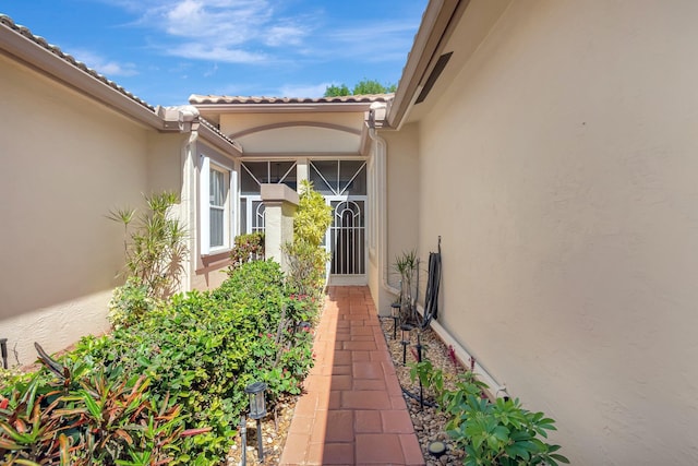 view of exterior entry with a tiled roof and stucco siding