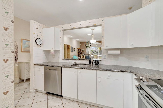 kitchen featuring a sink, appliances with stainless steel finishes, white cabinets, light tile patterned floors, and decorative backsplash